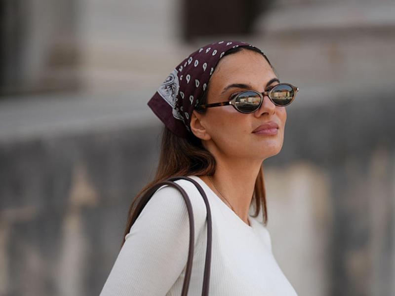 Frau mit Sonnenbrille trägt Bandana im Haar.