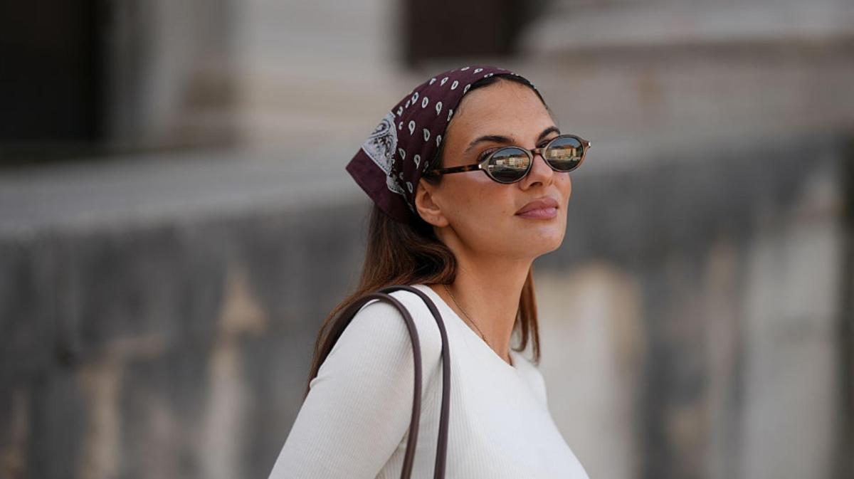 Frau mit Sonnenbrille trägt Bandana im Haar.
