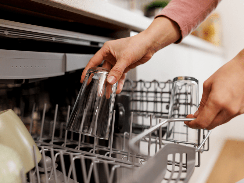 Frau räumt Geschirr ein.