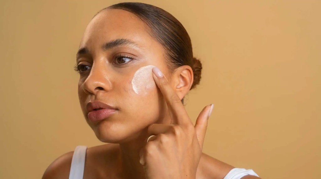 Frau tr&auml;gt Hautpflege auf ihr Gesicht auf