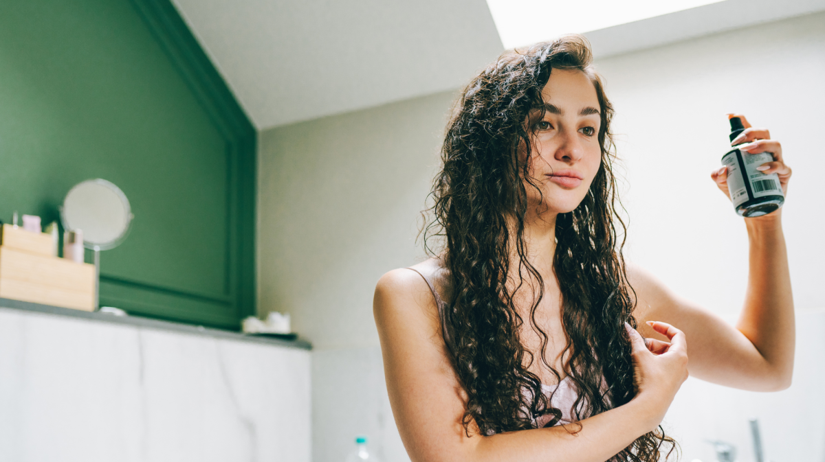 Frau, die ihre lockigen Haare nach dem Waschen stylt.