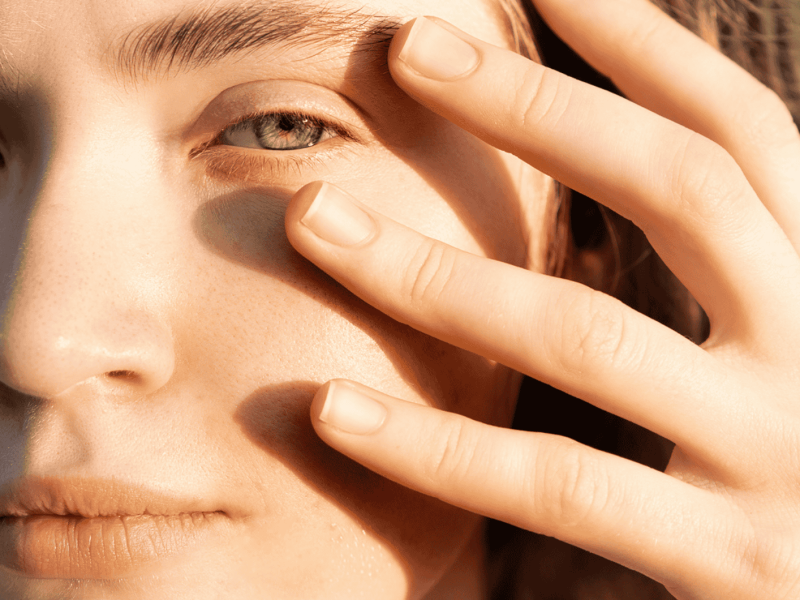 Eine junge Frau hält ihre Hand ans Gesicht.