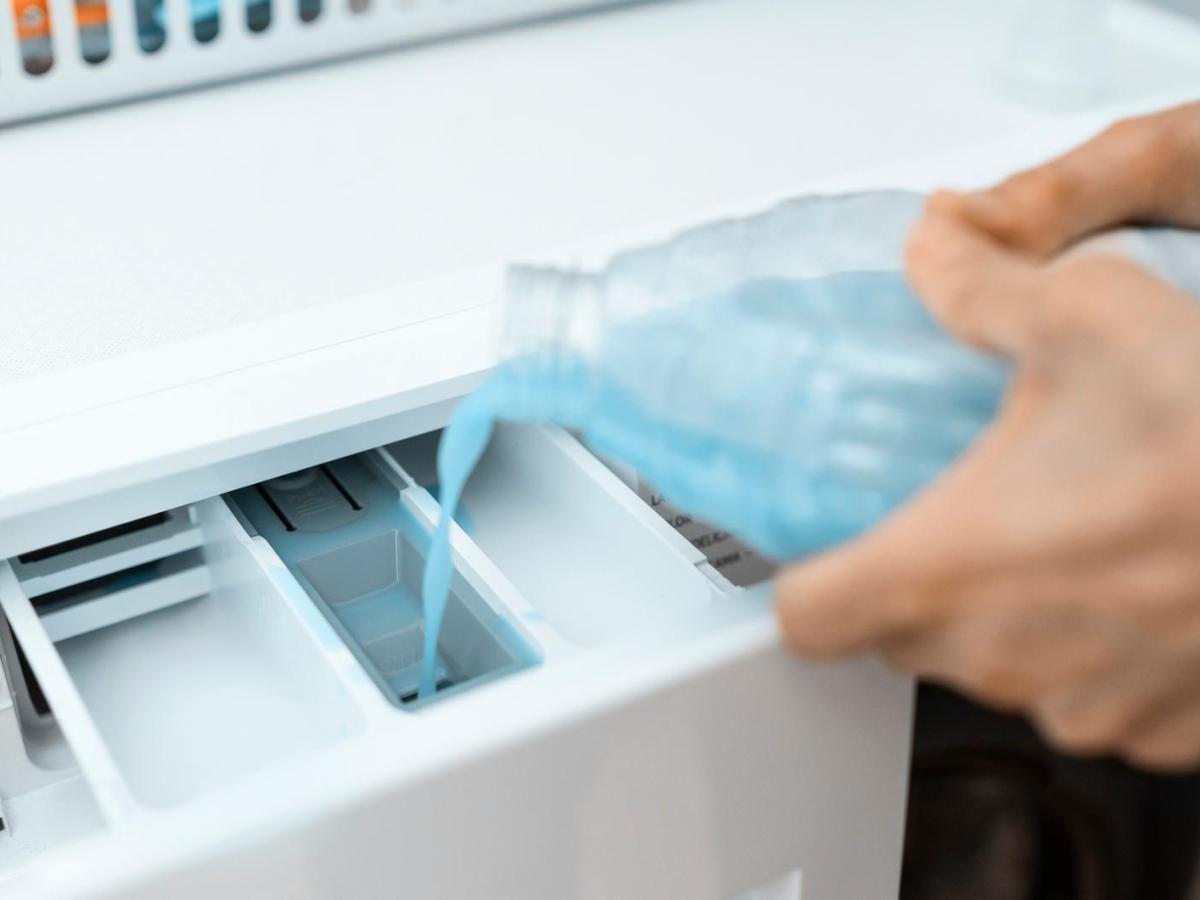 Frau füllt einen Reiniger in das Hauptfach der Waschmaschine.