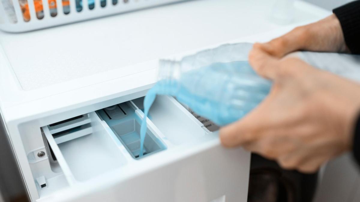 Frau füllt einen Reiniger in das Hauptfach der Waschmaschine.