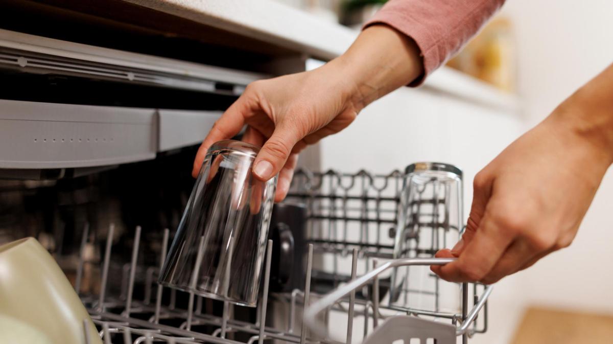 Frau räumt ein Glas aus der Spülmaschine.