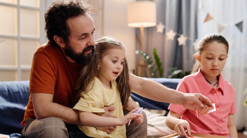 Vater spielt mit seinen Töchtern ein Brettspiel.