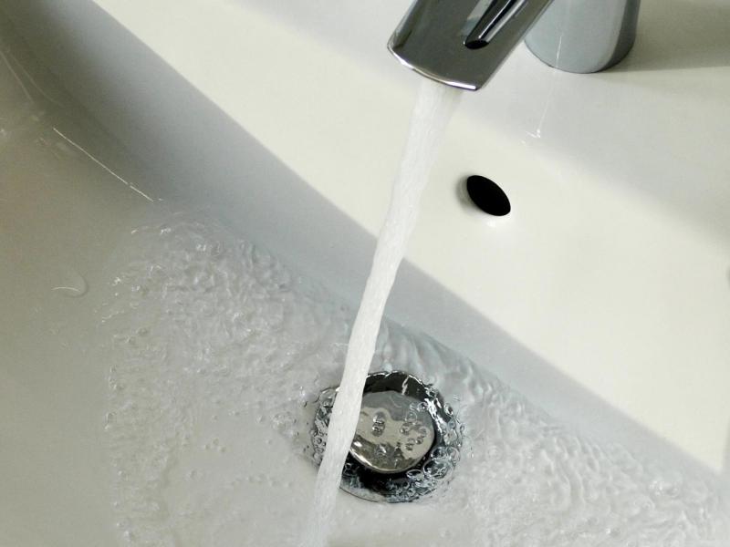 Wasser fließt aus dem Wasserhahn am Waschbecken im Badezimmer.