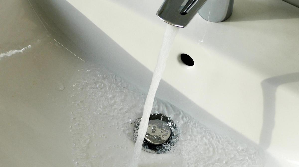 Wasser fließt aus dem Wasserhahn am Waschbecken im Badezimmer.