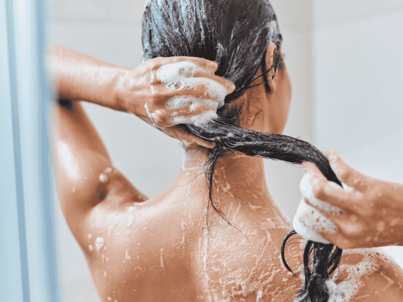 Frau wäscht ihre Haare nach Shampoo aus.