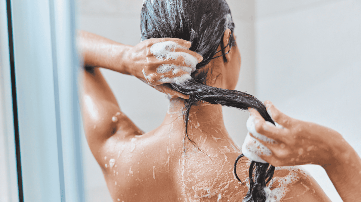 Frau wäscht ihre Haare nach Shampoo aus.