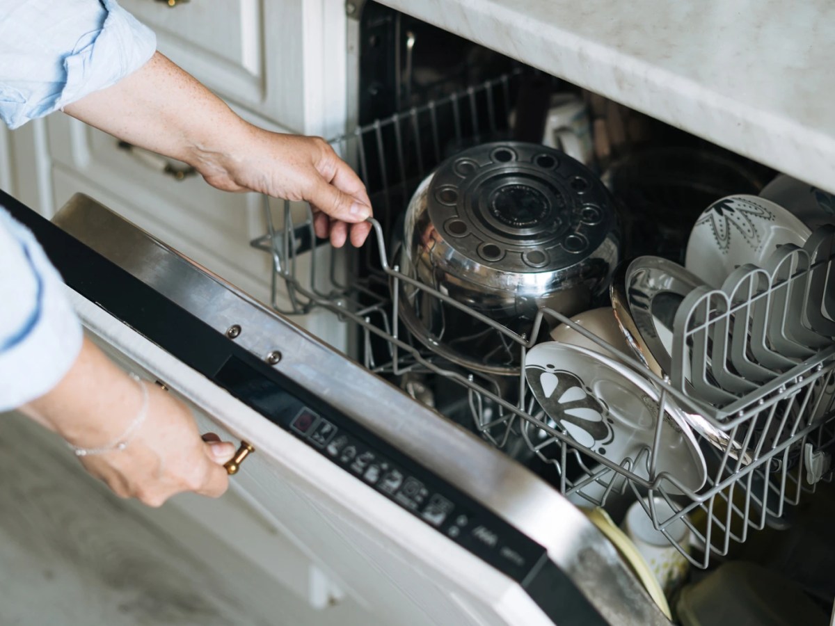 Frau &ouml;ffnet fertige Sp&uuml;lmaschine