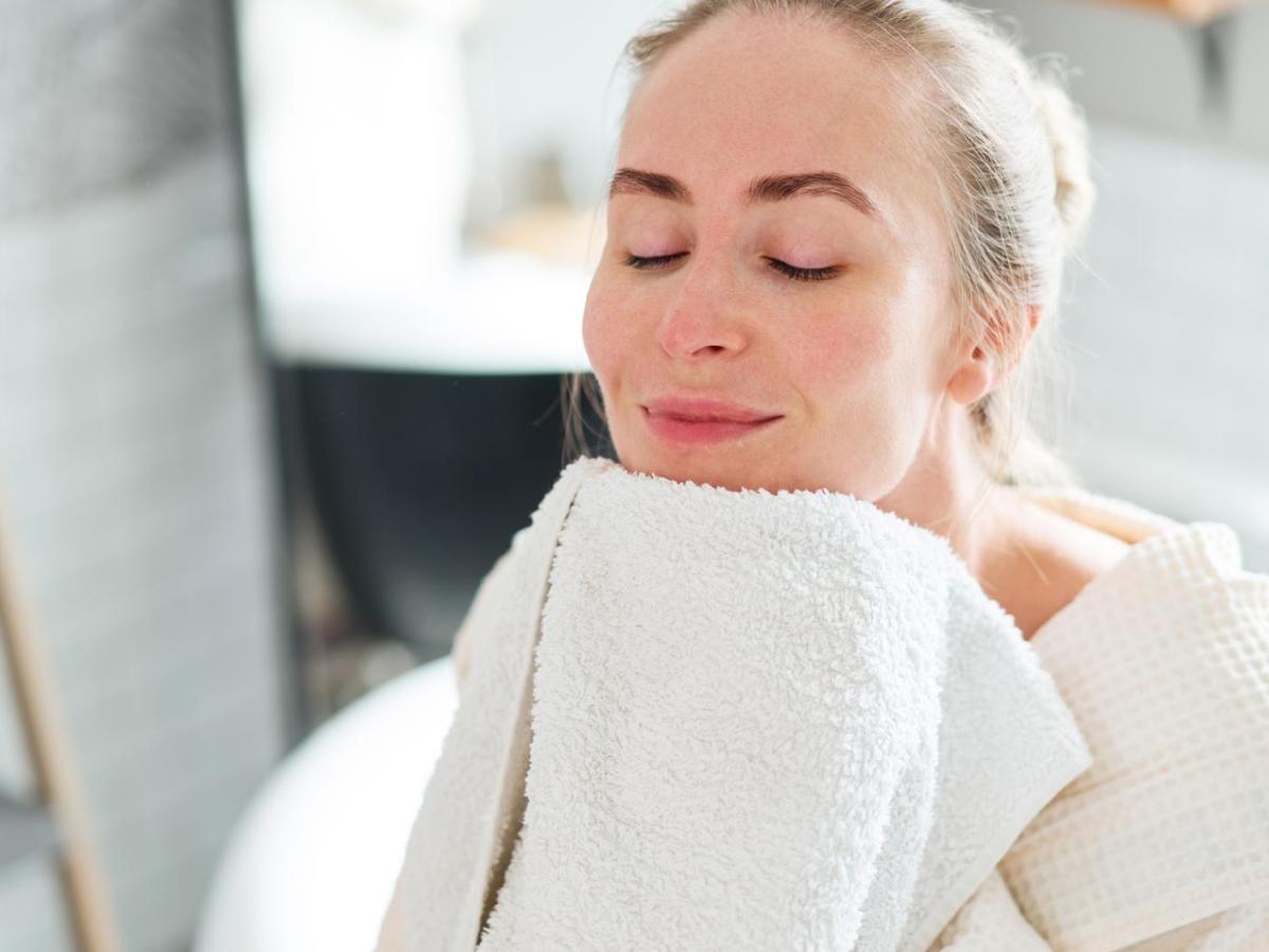 Frau reibt ihr Gesicht an ein Handtuch.