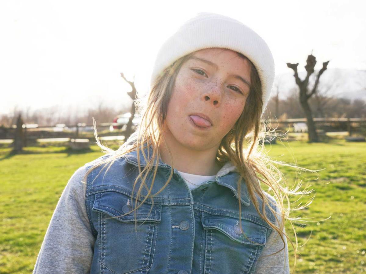 M&auml;dchen an einem sch&ouml;nen Herbsttag drau&szlig;en, streckt frech die Zunge raus.