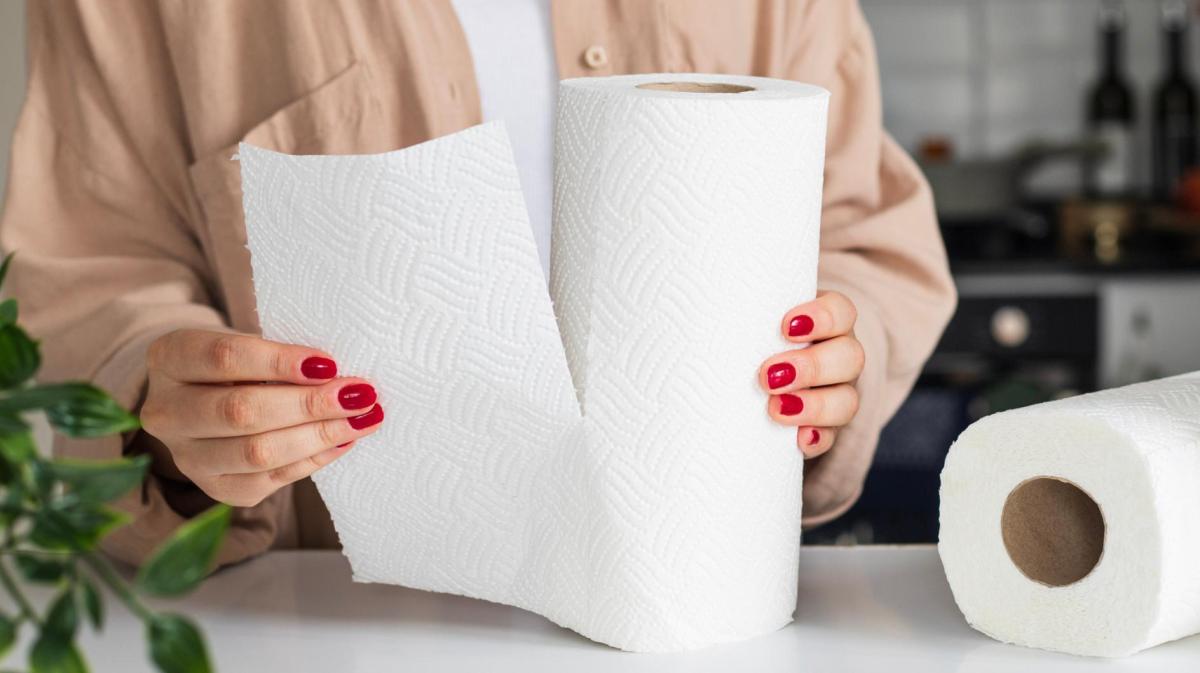 Frau mit roten Nägeln reißt ein Stück Küchenkrepp ab.