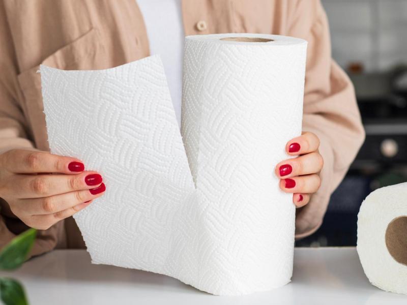 Frau mit roten Nägeln reißt ein Stück Küchenkrepp ab.