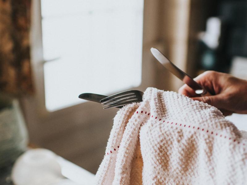 Frau reinigt Silberbesteck mit einem Tuch.
