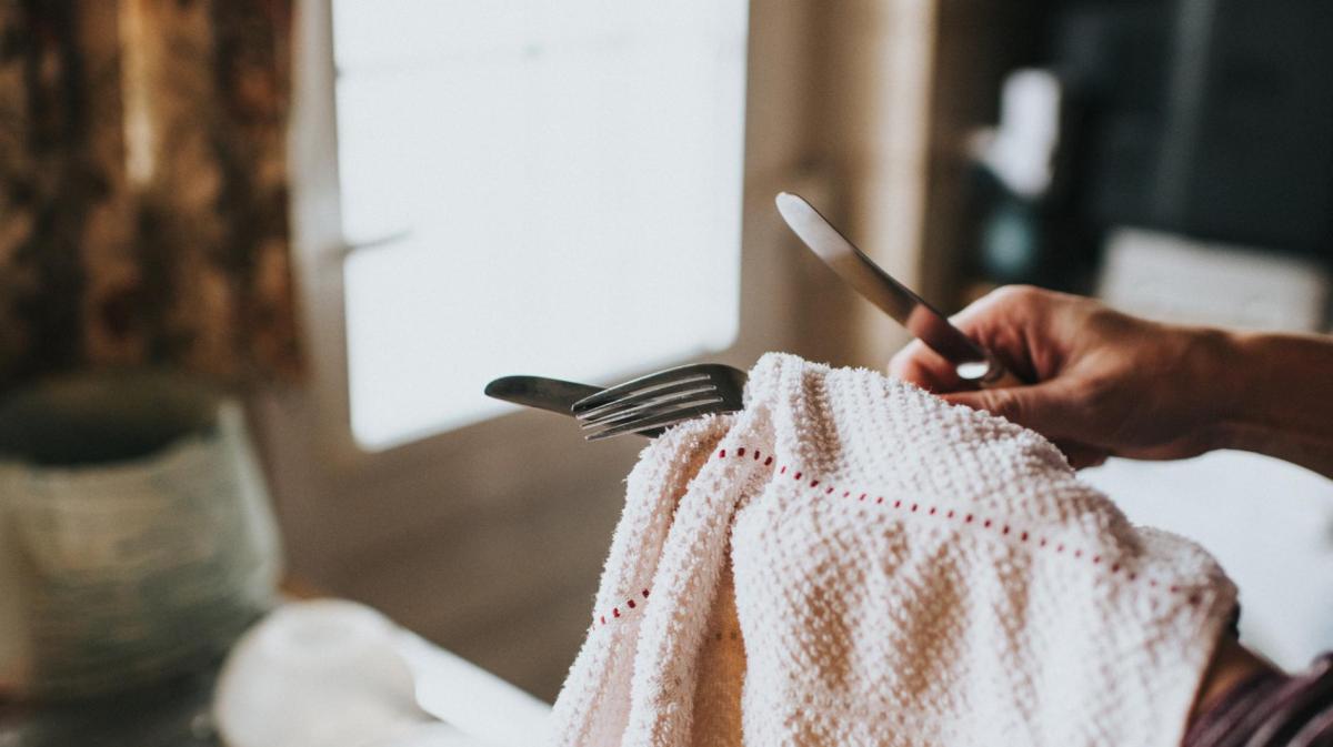 Frau reinigt Silberbesteck mit einem Tuch.