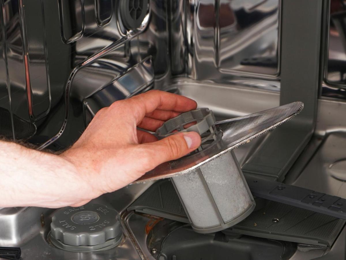 Frau entnimmt den Spülmaschinen-Filter.