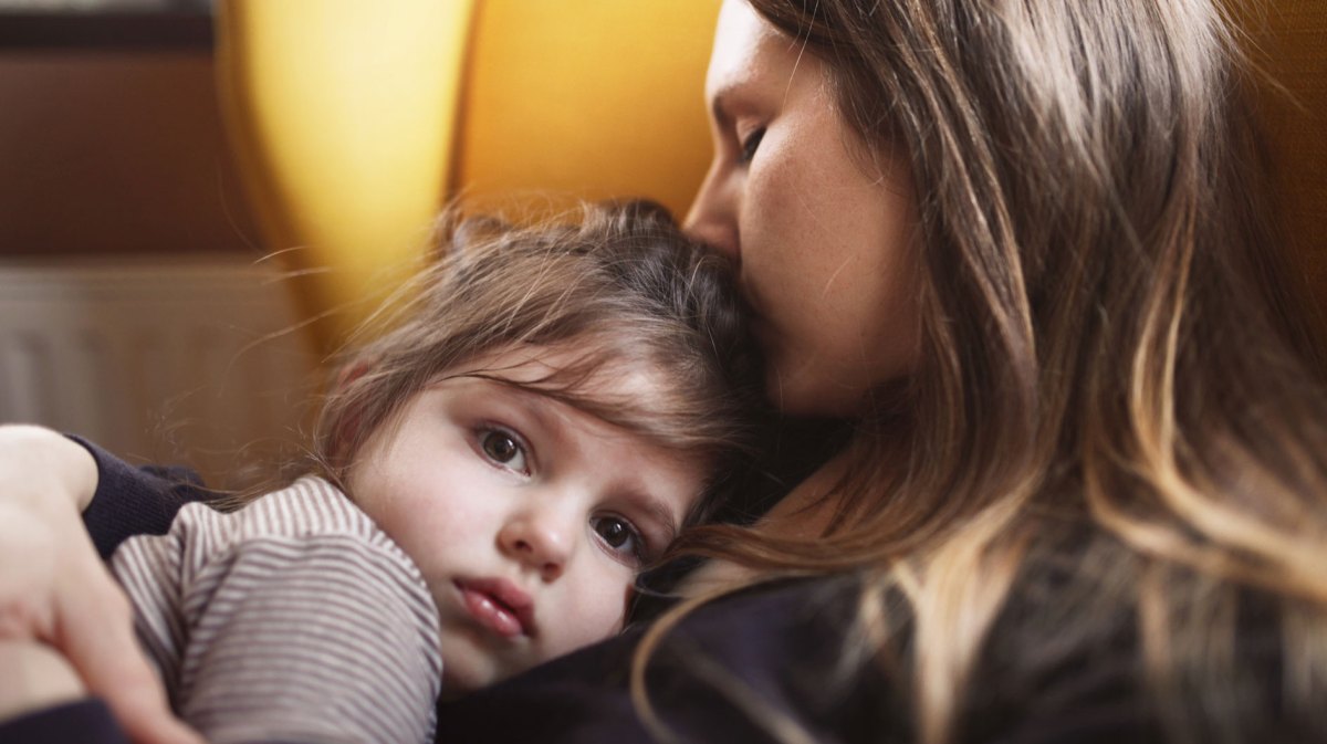 Mutter und Tochter kuscheln auf einem gelben Sessel.
