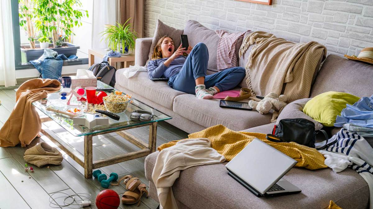 Teenagermädchen liegt auf dem Sofa, um sie herum herrscht Chaos.