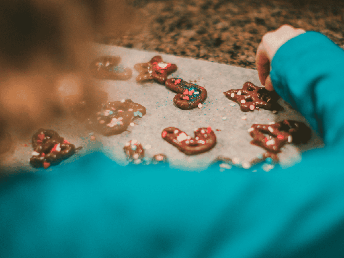 Kind dekoriert Schoko-Brezel-Plätzchen.