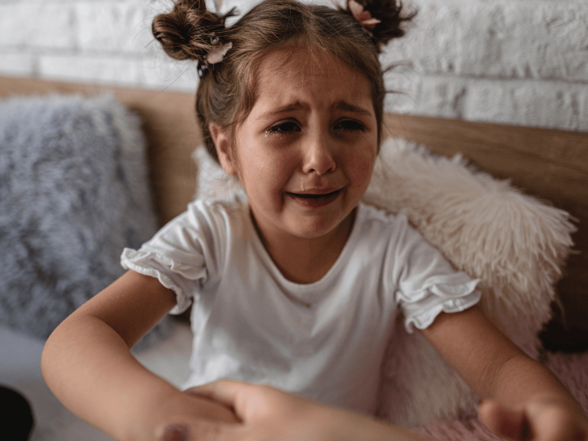 Kind sitzt in Kita auf der Couch und weint sehr stark.