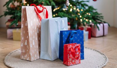 Die Griffe der Geschenktüten haben eine geniale Zusatzfunktion Geschenktüten vor Weihnachtsvbaum