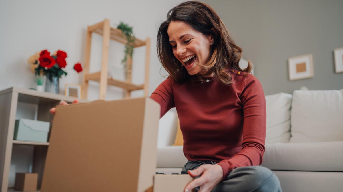 Frau packt ein Geschenk aus und freut sich riesig.