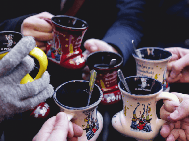 Mehrere Personen stoßen mit Glühweintassen an.