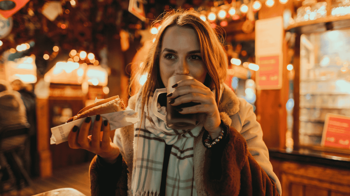 Frau trinkt Glühwein auf Weihnachtsmarkt.