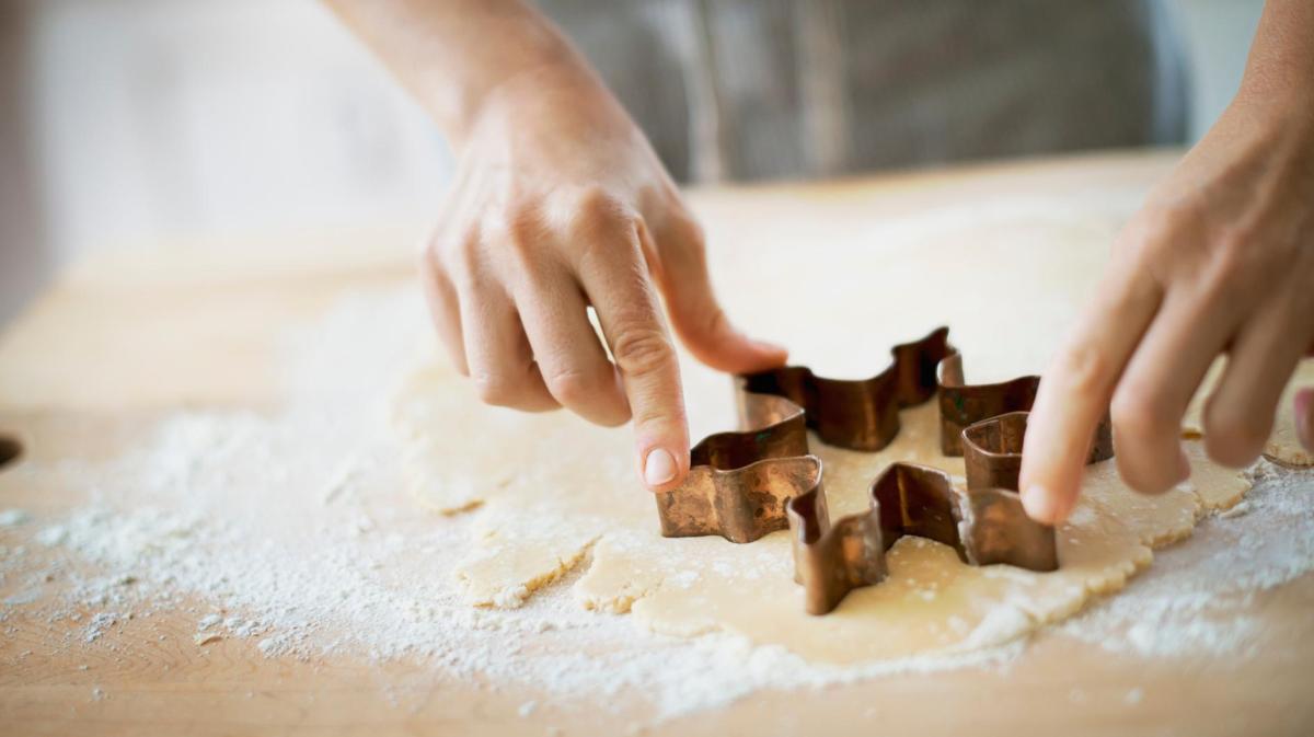 Frau sticht einen Stern aus Mürbeteig aus.