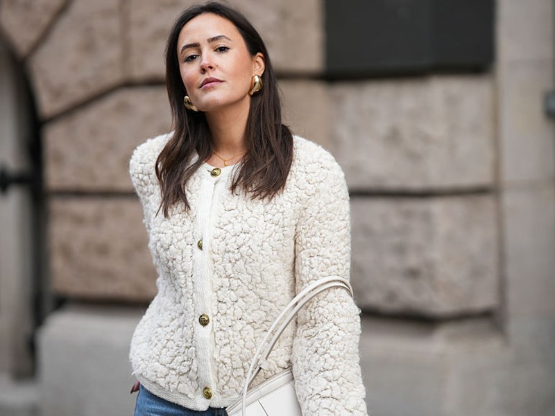 BERLIN, GERMANY - NOVEMBER 25: Laura Noltemeyer is seen wearing a cream textured bouclé knit cardigan with a structured silhouette and gold button fastening from Massimo Dutti; light-blue straight-leg denim trousers with a soft fading in a classic cut from Zara; a white structured leather top-handle bag in an intrecciato weave and trapeze silhouette called “Intrecciato Tote” from Bottega Veneta; chunky sculptural gold earrings from Zara; her dark brown hair is worn loose, straight and parted in the middle on November 25, 2025 in Berlin, Germany.