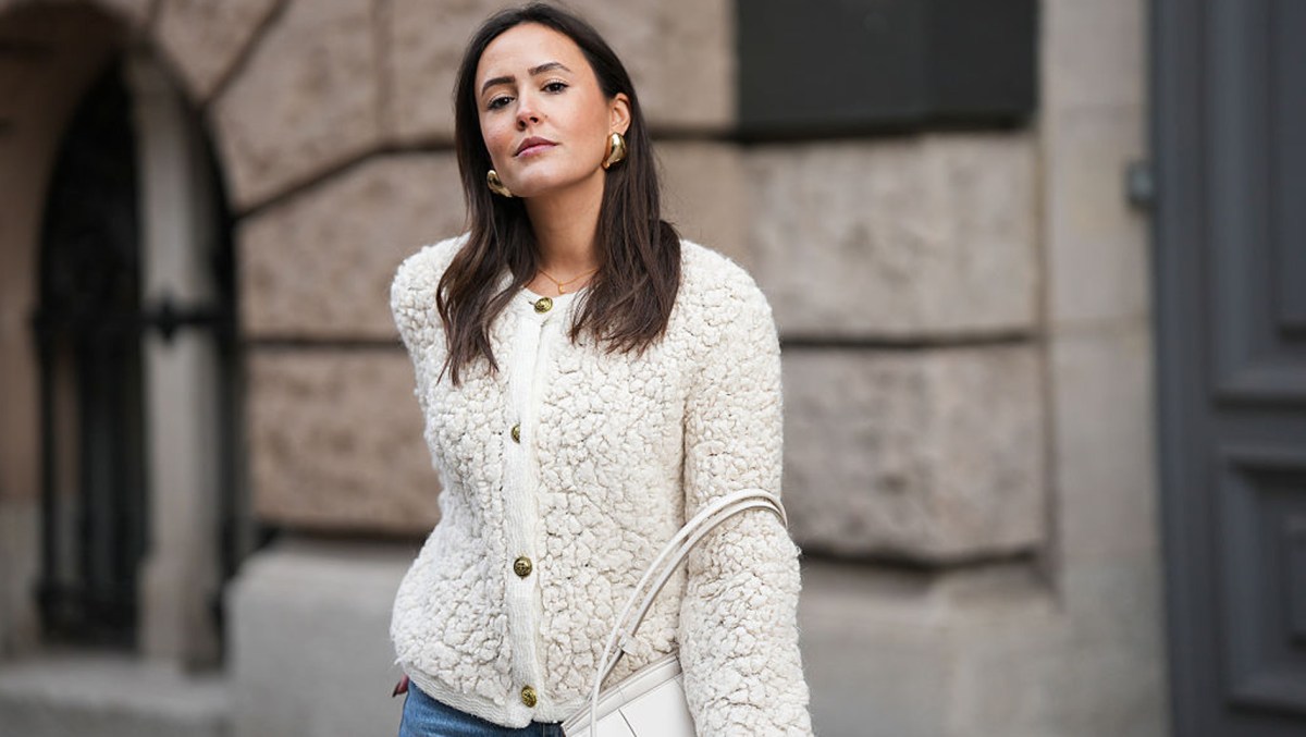 BERLIN, GERMANY - NOVEMBER 25: Laura Noltemeyer is seen wearing a cream textured bouclé knit cardigan with a structured silhouette and gold button fastening from Massimo Dutti; light-blue straight-leg denim trousers with a soft fading in a classic cut from Zara; a white structured leather top-handle bag in an intrecciato weave and trapeze silhouette called “Intrecciato Tote” from Bottega Veneta; chunky sculptural gold earrings from Zara; her dark brown hair is worn loose, straight and parted in the middle on November 25, 2025 in Berlin, Germany.
