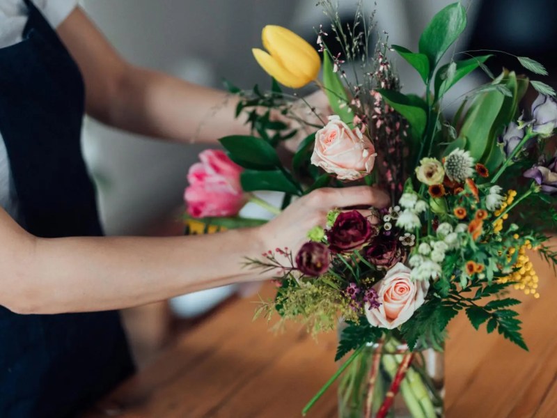Frau stellt Blumen in eine Vase.