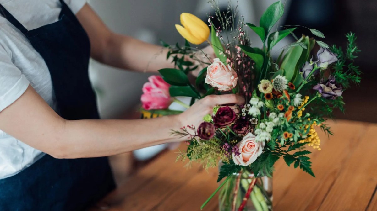 Frau stellt Blumen in eine Vase.
