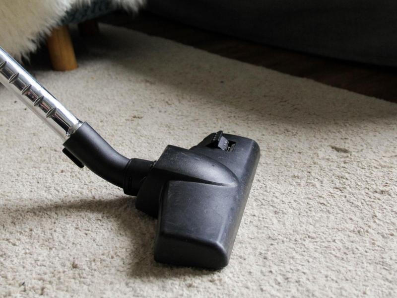 Ein Teppich wird mit einem Staubsauger abgesaugt.