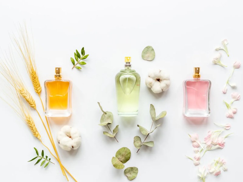 Mehrere Parfumflakons mit Bl&uuml;ten im Hintergrund
