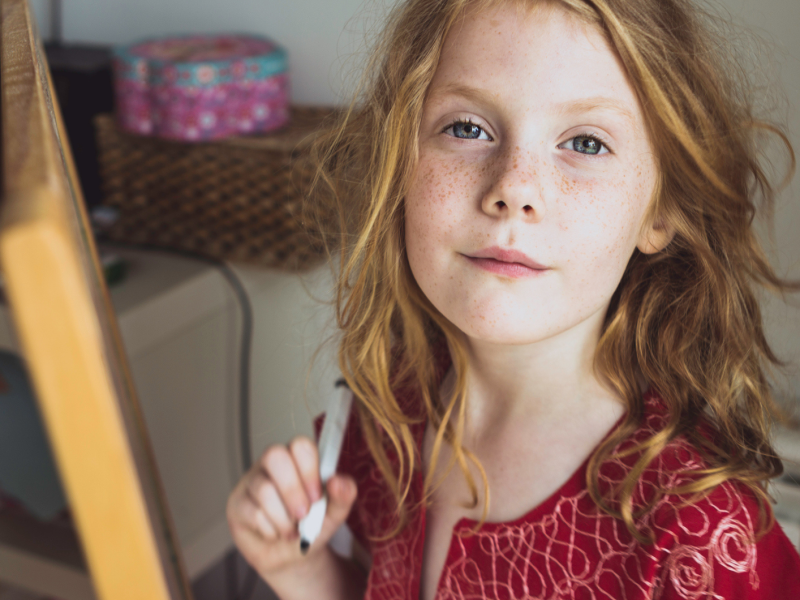 M&auml;dchen mit roten Haaren und einem Stift in der Hand schaut selbstbewusst