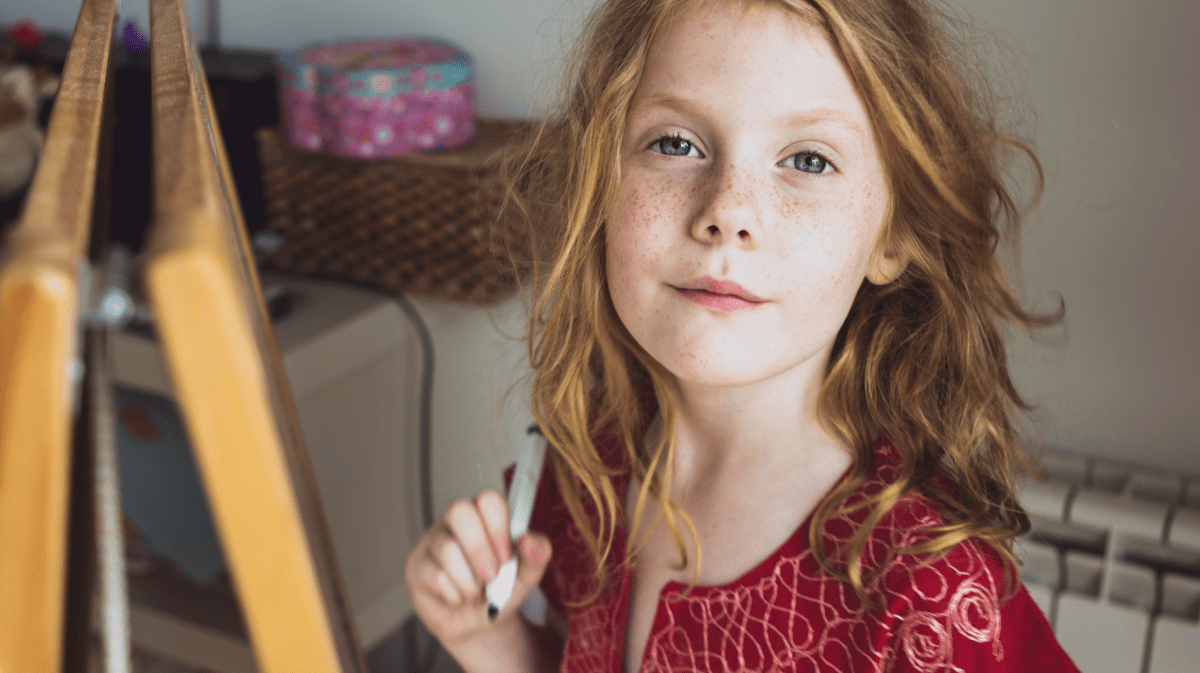 Mädchen mit roten Haaren und einem Stift in der Hand schaut selbstbewusst