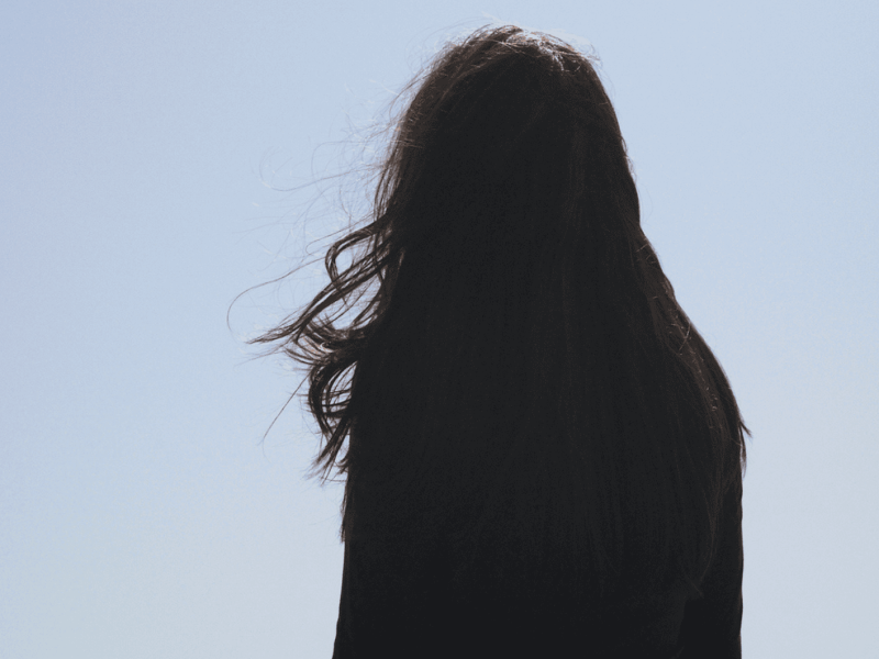 Frau mit langen dunklen Haaren schaut in die Ferne