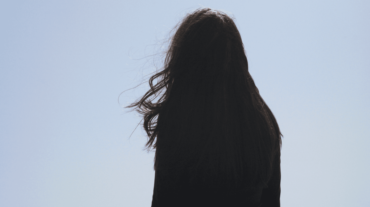 Frau mit langen dunklen Haaren schaut in die Ferne