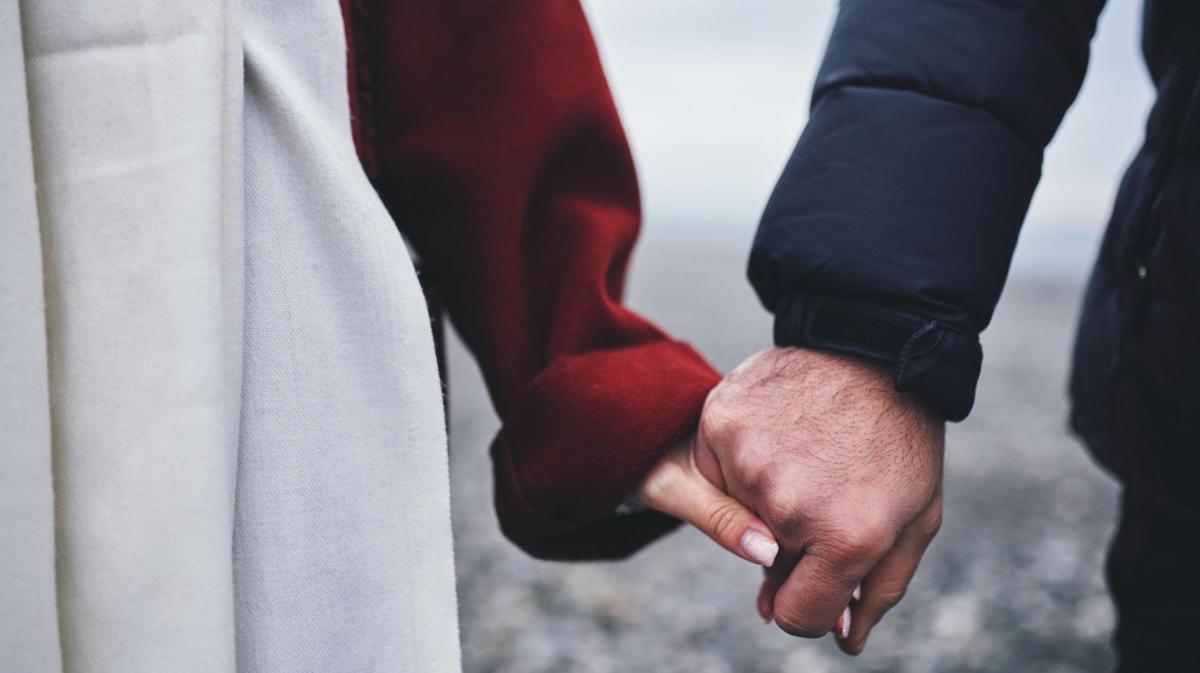 Frau und Mann halten Händchen und sind draußen im Winter.