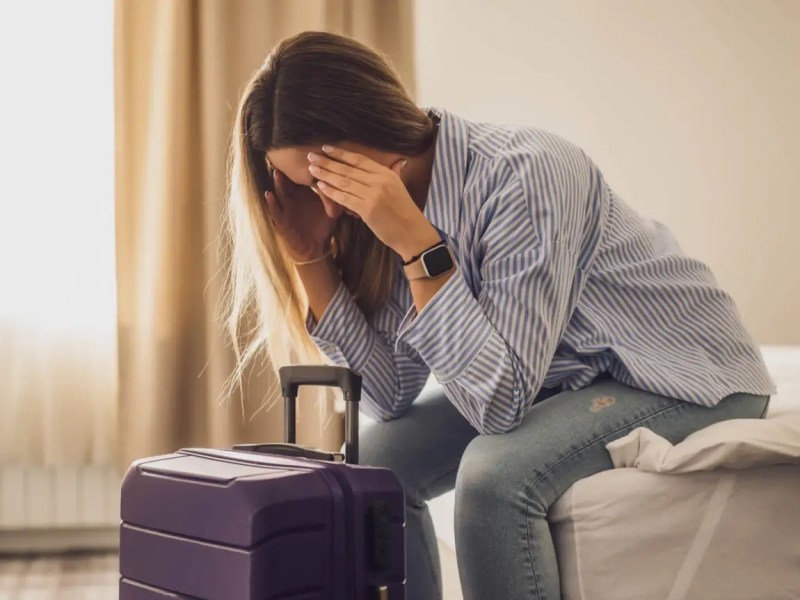 Frau sitzt im Hotelzimmer und hält sich die Hände vors Gesicht
