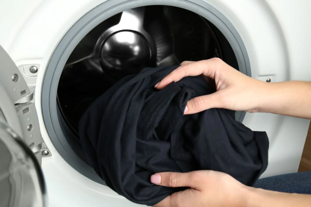 Hände nehmen schwarze Wäsche aus Waschmaschine