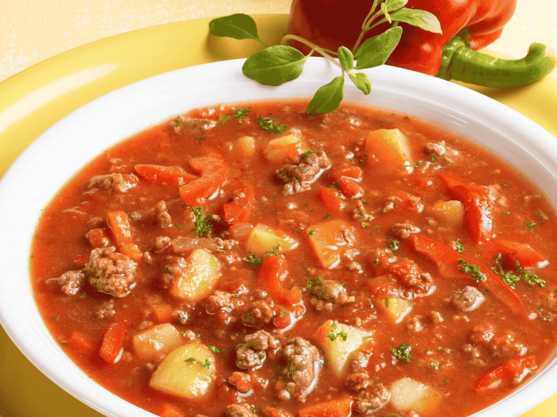 Bauerntopf mit veganem Hackfleisch, Kartoffeln, Paprika und Tomaten in einer wei&szlig;en Sch&uuml;ssel.