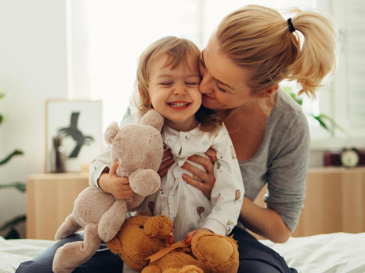Mutter mit ihrem Kleinkind, das Kuscheltiere in der Hand hat.