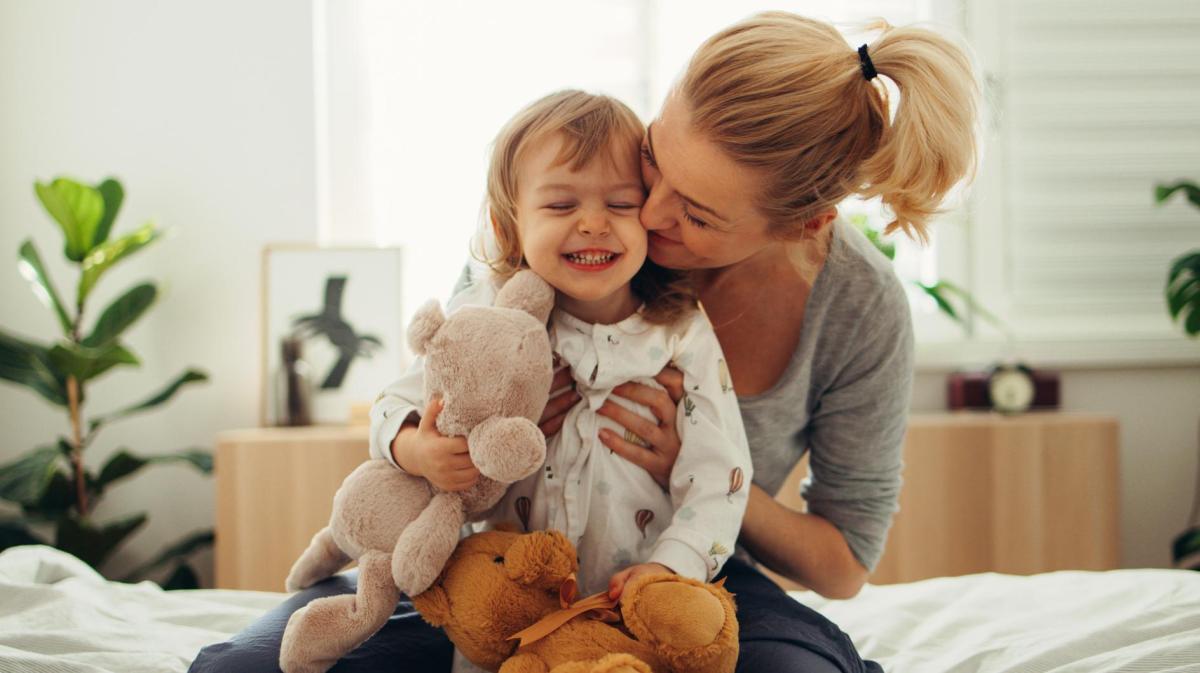Mutter mit ihrem Kleinkind, das Kuscheltiere in der Hand hat.