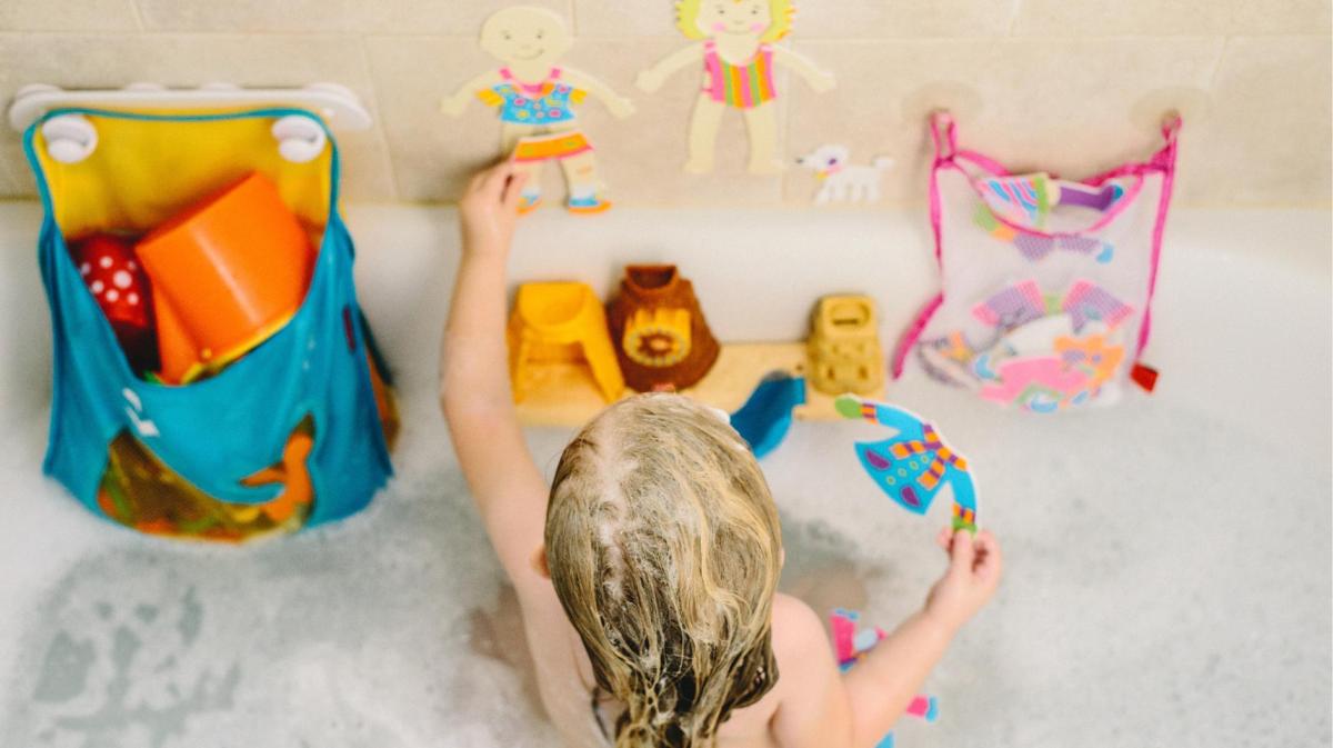 Kind spielt mit Wasserspielzeug in der Badewanne.