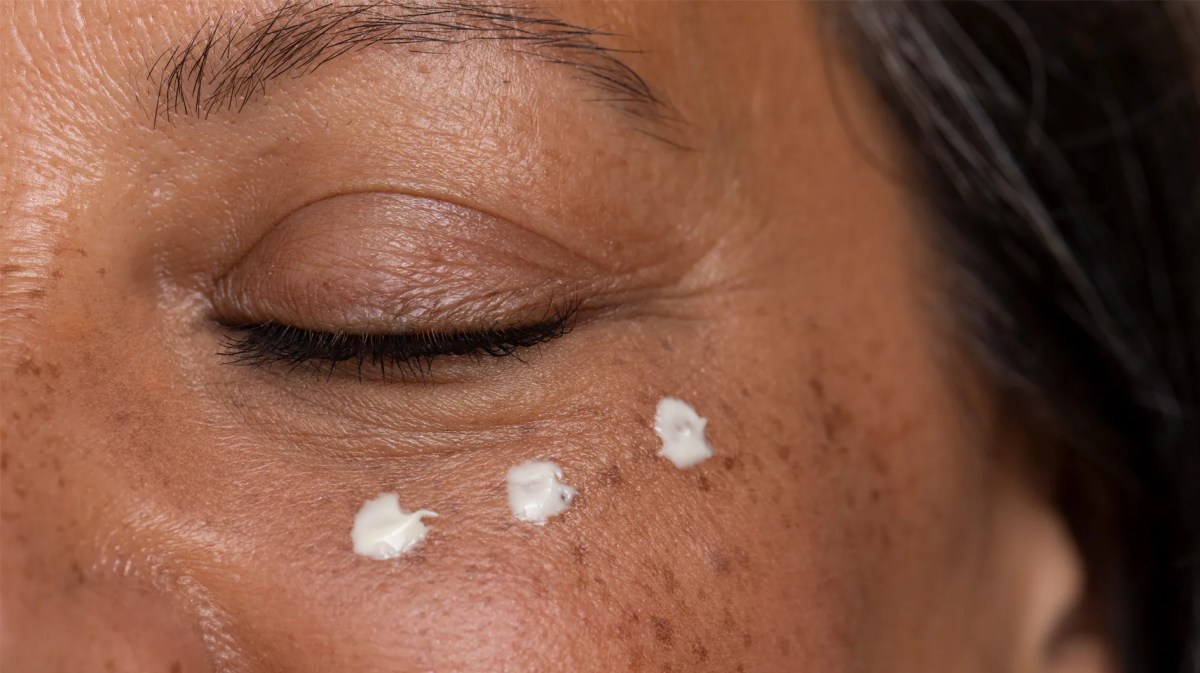 Frau, die unter den Augen 3 Tropfen einer Creme aufgetragen hat.