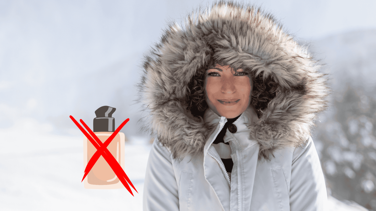 Junge Frau streht mit dicker Winterjacke und Kapuze auf dem Kopf in Schneelandschaft